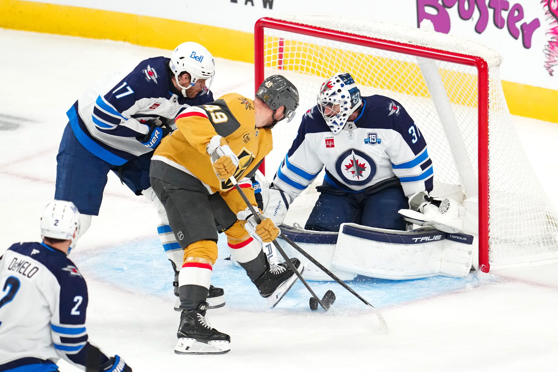 Winnipeg Jets center Adam Lowry (17) breaks up a scoring chance by Vegas Golden Knights left wing Ivan Barbashev (49) as goaltender Connor Hellebuyck (37) defends his net during the third period at T-Mobile Arena.