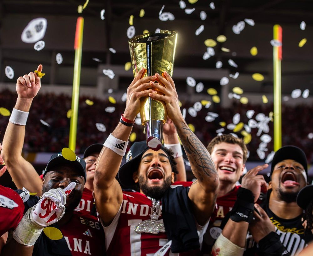 Indiana's Elijah Sarratt (13) lifts the trophy as Tyrique Tucker (95), Charlie Becker (80), Fernando Mendoza (15), and Mikail Kamara (6) celebrate on the podium after the College Football Playoff National Championship college football game at Hard Rock Stadium in Miami Gardens on Monday, Jan. 19, 2026.