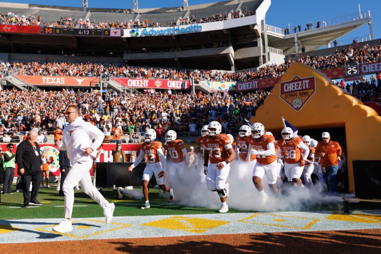 Texas Longhorns head coach Steve Sarkisian, Texas Longhorns wide receiver Parker Livingstone (13) and offensive lineman Brandon Baker (73) run onto the field before a game against the Michigan Wolverines at Camping World Stadium.