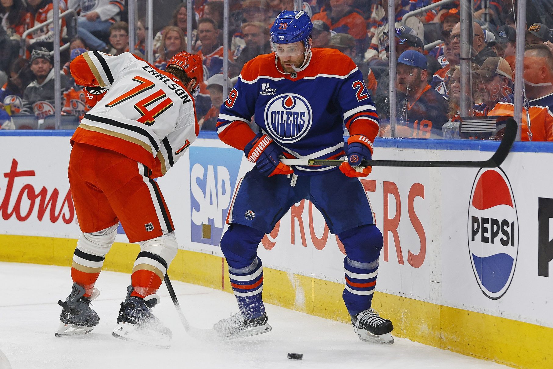 Anaheim Ducks defensemen John Carlson (74) and Edmonton Oilers forward Leon Draisaitl (29) battle along the boards for a loose puck during the third period in game five of the first round of the 2026 Stanley Cup Playoffs at Rogers Place.