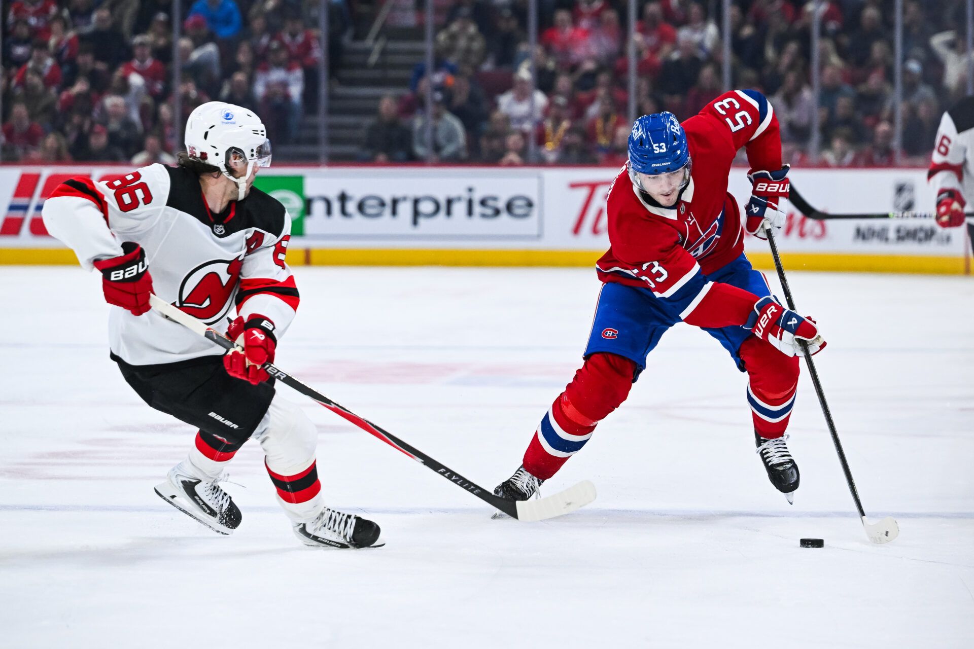 Montreal Canadiens defenseman Noah Dobson (53) plays the puck against New Jersey Devils center Jack Hughes (86) during the third period at Bell Centre.