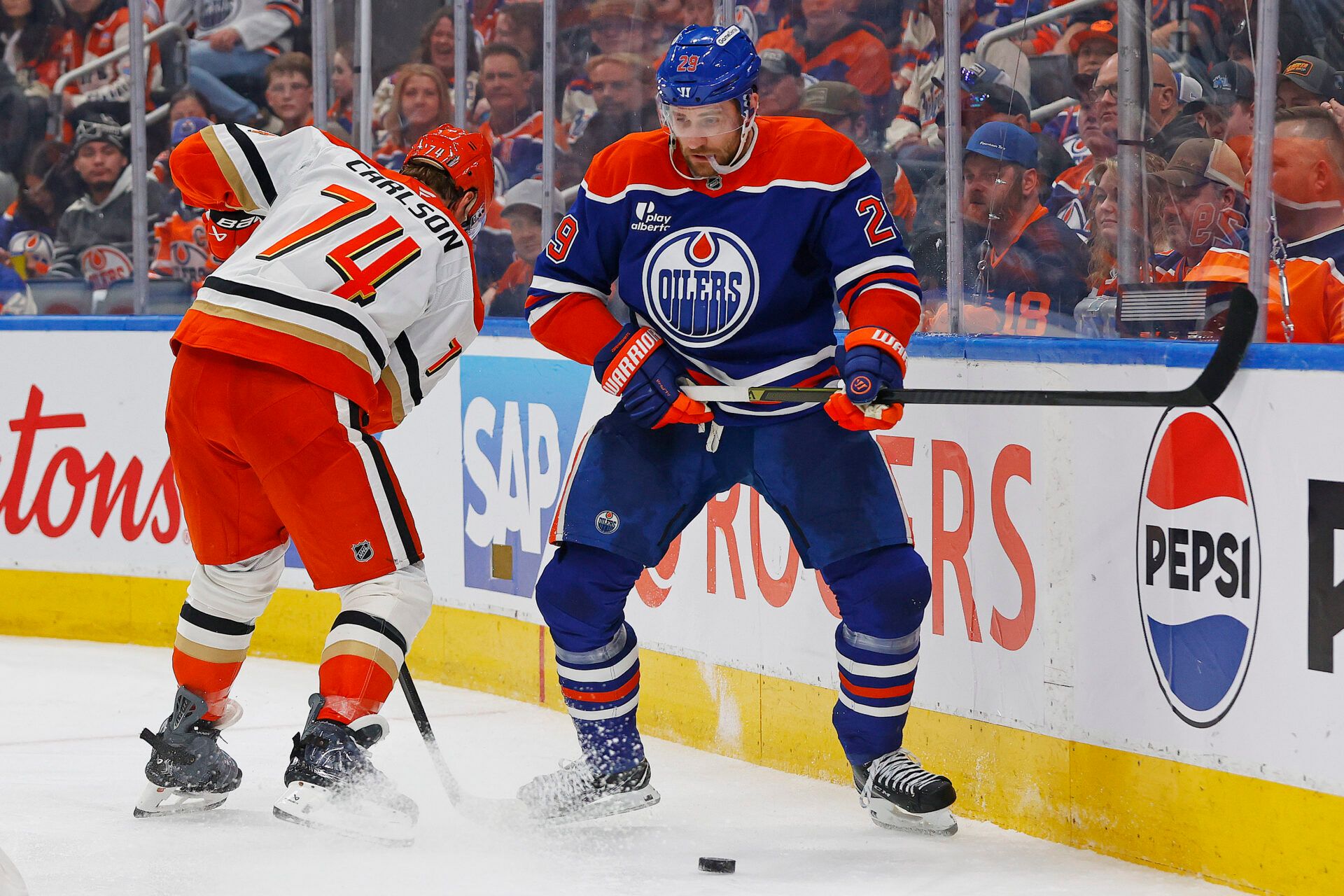 Anaheim Ducks defensemen John Carlson (74) and Edmonton Oilers forward Leon Draisaitl (29) battle along the boards for a loose puck during the third period in game five of the first round of the 2026 Stanley Cup Playoffs at Rogers Place.