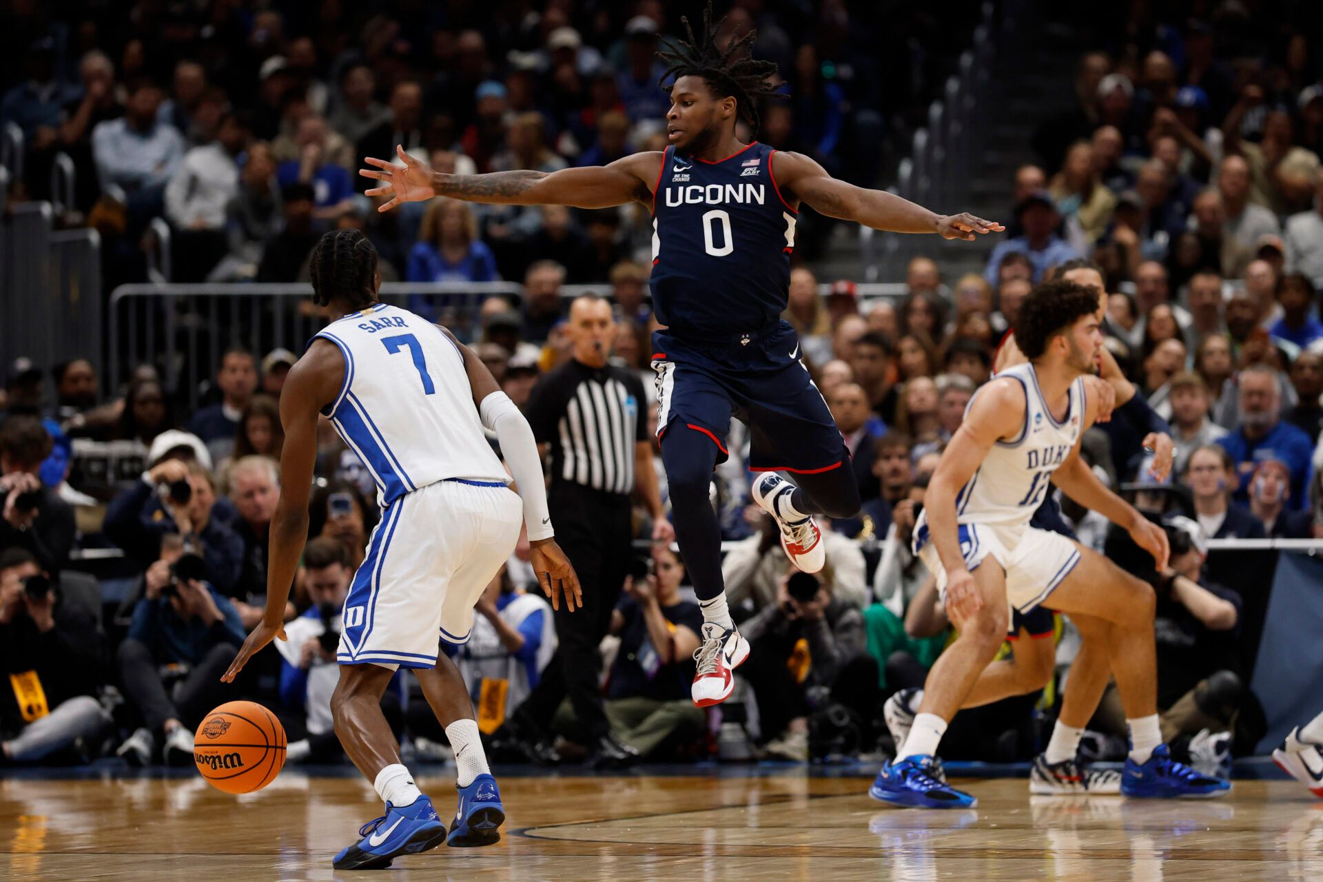 Duke Blue Devils guard Dame Sarr (7) dribbles the ball past UConn Huskies guard Malachi Smith (0) during an Elite Eight game of the East Regional of the men's 2026 NCAA Tournament at Capital One Arena.
