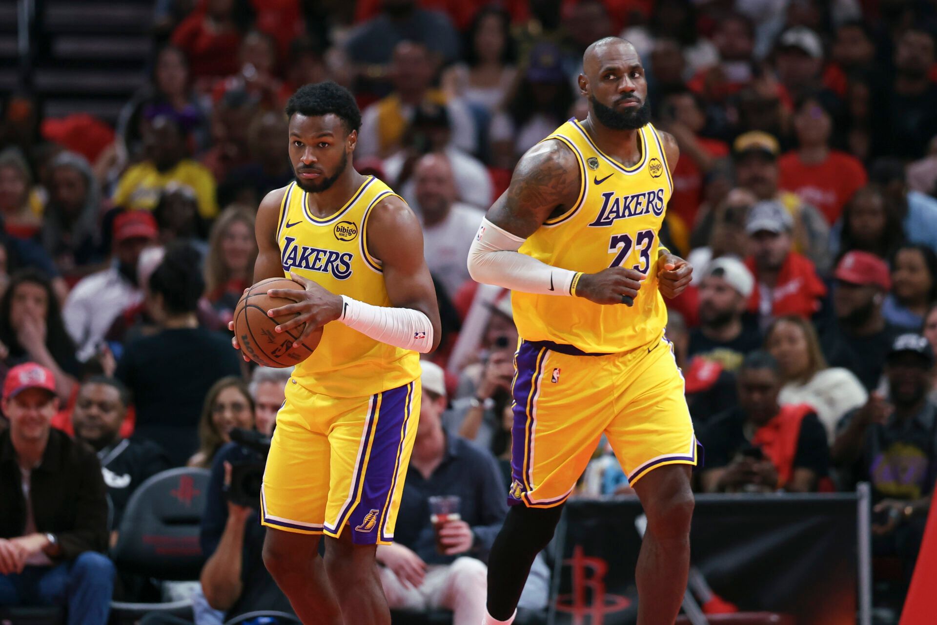 Los Angeles Lakers forward LeBron James (23) gives the ball to guard Bronny James (9) during the fourth quarter against the Houston Rockets during game three of the first round of the 2026 NBA Playoffs at Toyota Center.