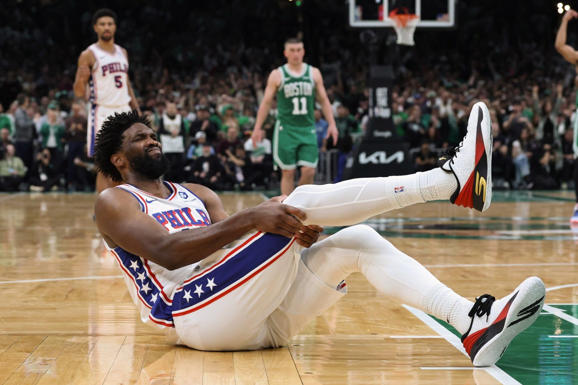 Philadelphia 76ers center Joel Embiid (21) grabs his leg after going down during the second half of game seven of the first round of the 2026 NBA Playoffs against the Boston Celtics at TD Garden.