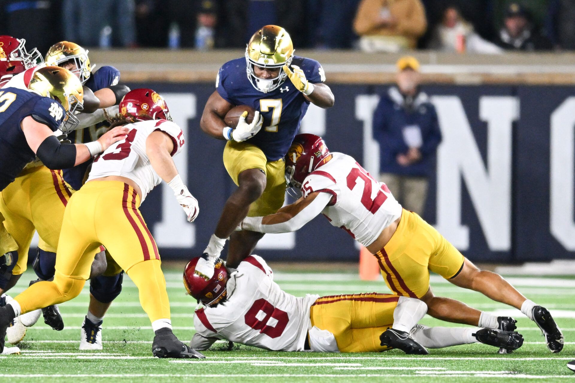 Notre Dame Fighting Irish running back Audric Estime (7) jumps over USC Trojans safety Zion Branch (8) and linebacker Tackett Curtis (25) in the fourth quarter at Notre Dame Stadium.