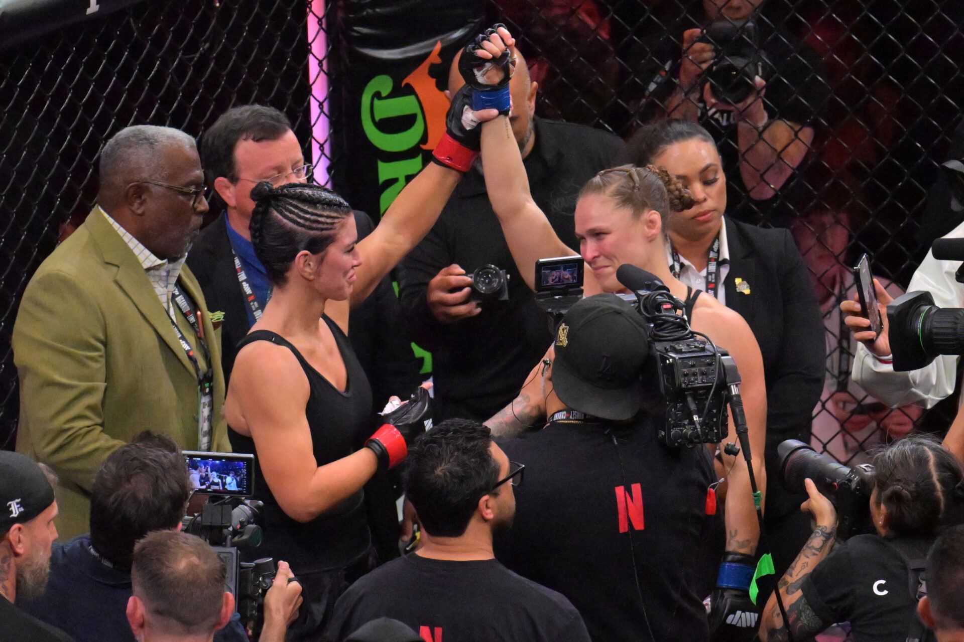 Ronda Rousey (blue gloves) celebrates defeating Gina Carano (red gloves) after a women's featherweight bout at Intuit Dome.