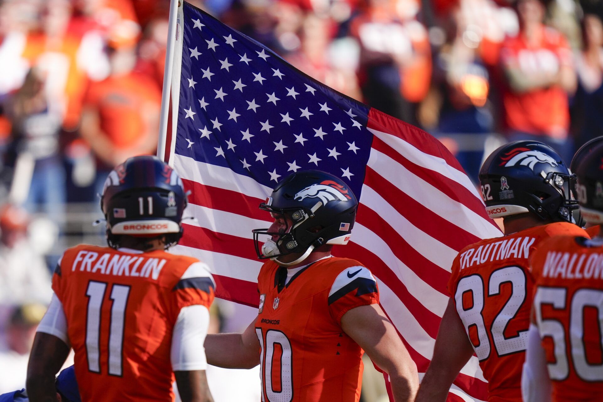 Denver Broncos quarterback Bo Nix (10) carries an American flag prior to the game against the Kansas City Chiefs at Empower Field at Mile High.