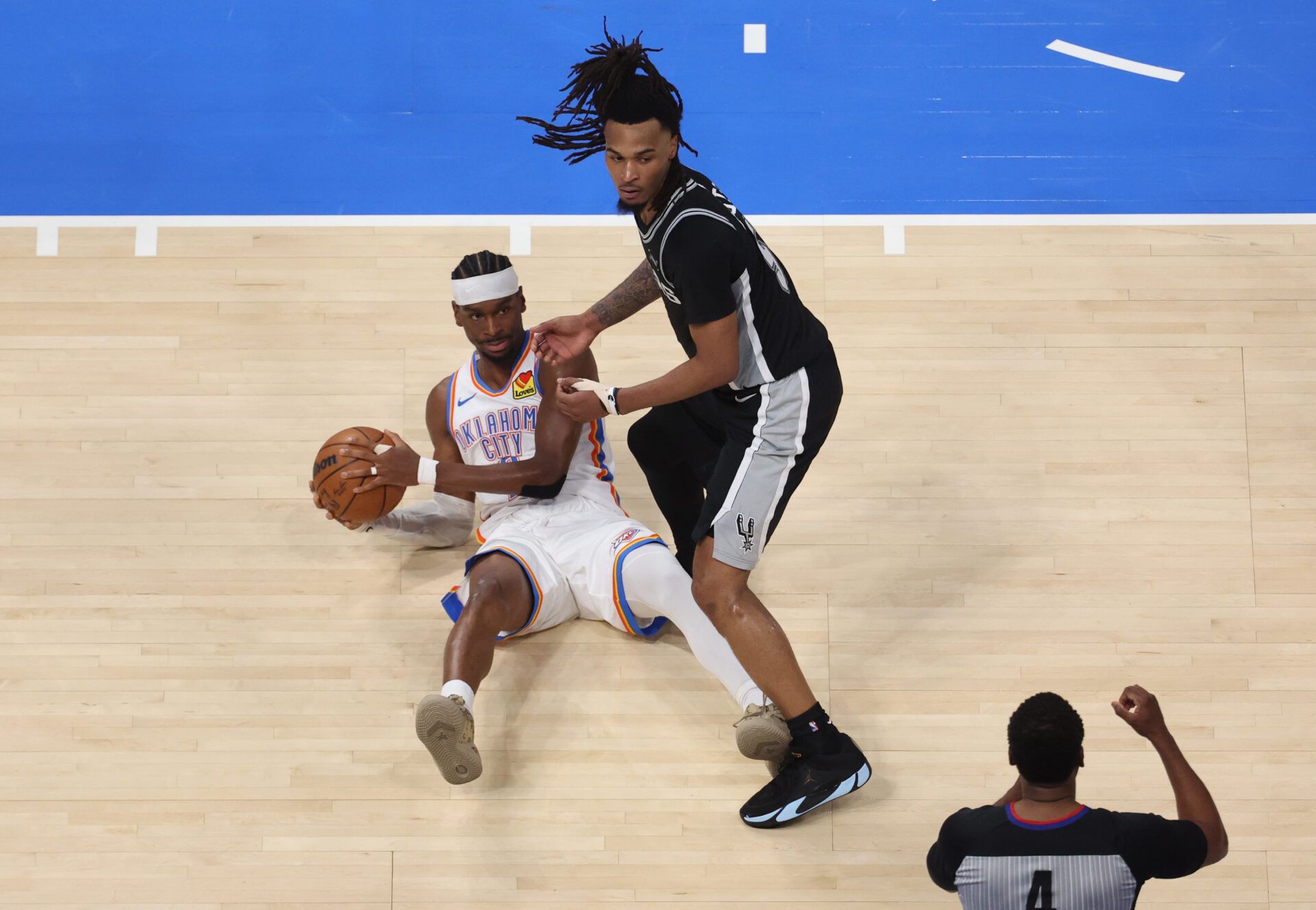 Oklahoma City Thunder guard Shai Gilgeous-Alexander (2) and San Antonio Spurs guard Stephon Castle (5) look at referee Sean Wright (4) after a call during the second quarter in game five of the western conference finals for the 2026 NBA playoffs at Paycom Center.