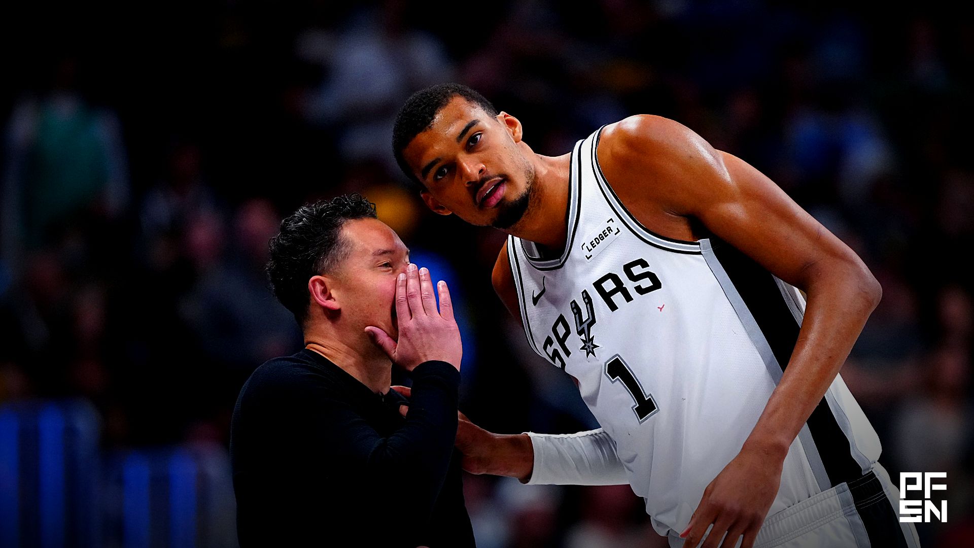 San Antonio Spurs forward Victor Wembanyama (1) listens to head coach Mitch Johnson in the fourth quarter against the Denver Nuggets at Ball Arena.