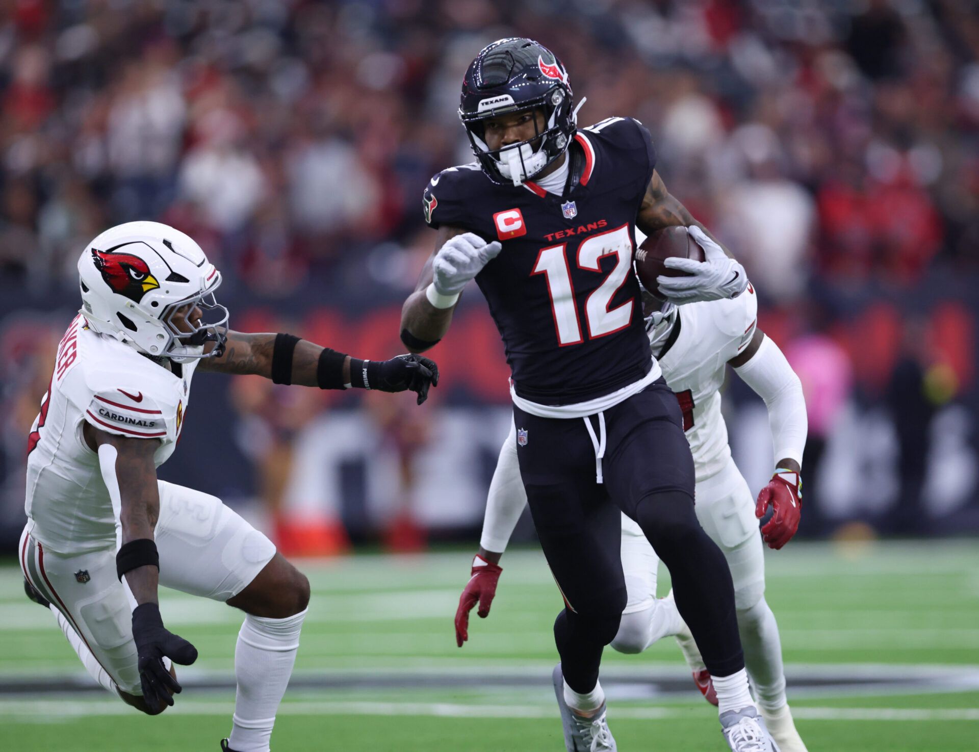 Houston Texans wide receiver Nico Collins (12) runs for a gain past Arizona Cardinals safety Budda Baker (3) during the first quarter at NRG Stadium.