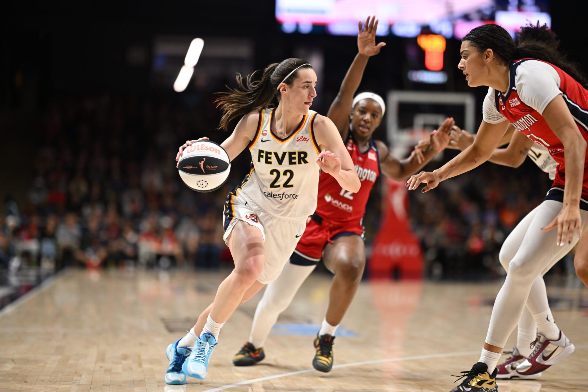 Indiana Fever guard Caitlin Clark (22) attempts to dribble past Washington Mystics center Lauren Betts (51) during the third quarter at CareFirst Arena.