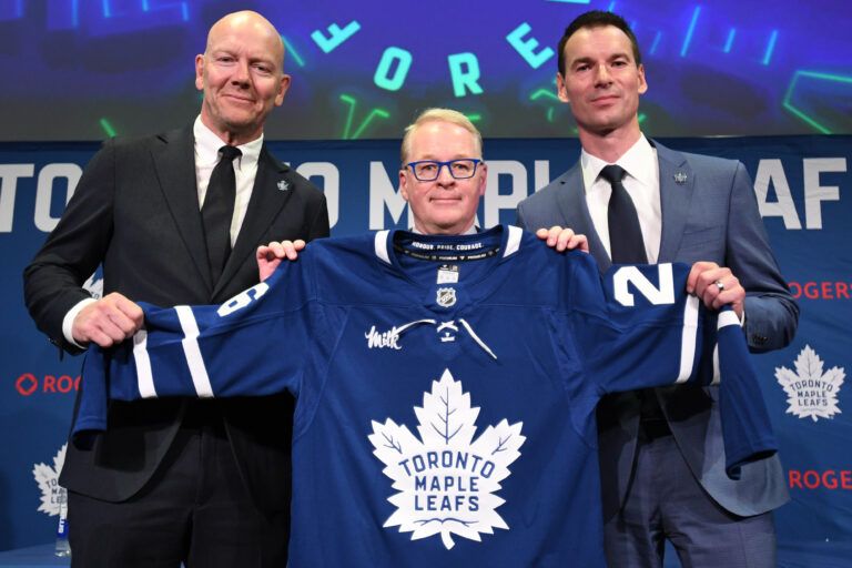 Maple Leaf Sports and Entertainment CEO Keith Pelley holds a team jersey between Toronto Maple Leafs general manager John Chayka (right) and senior executive advisor Mats Sundin at Real Sports Bar and Grill.