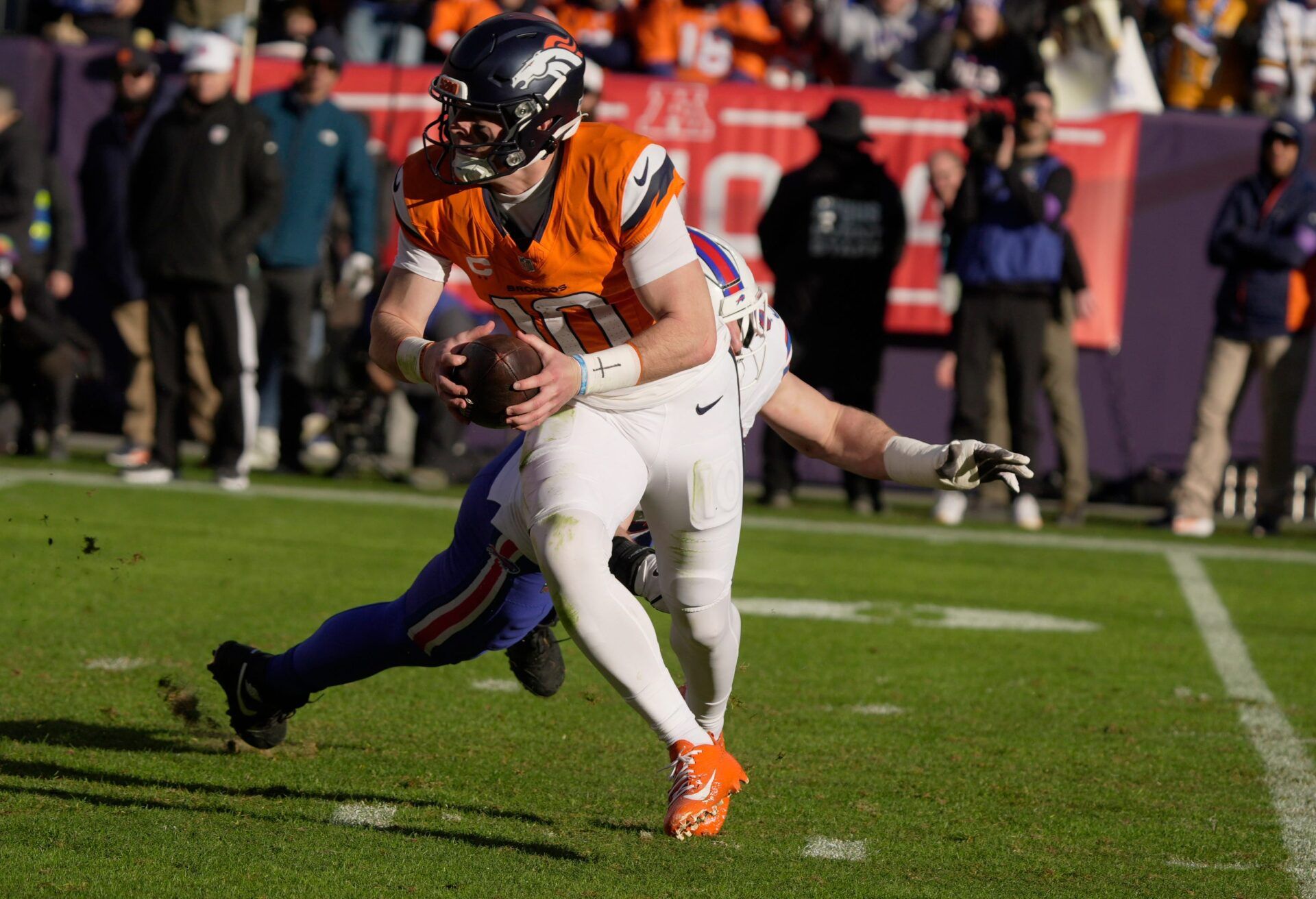 Denver Broncos quarterback Bo Nix avoids Buffalo Bills defensive end Joey Bosa after scooping up the loose ball that came towards him after running back RJ Harvey’s missed Nix’s toss to him during first half action at Empower FIeld at Mile High in Denver, Colorado on Jan. 17, 2026.