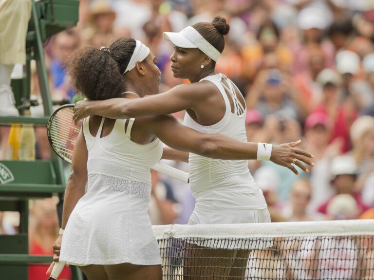 Serena Williams (USA) and Venus Williams (USA) hug at the net after their match on day seven of The Championships Wimbledon at the AELTC.