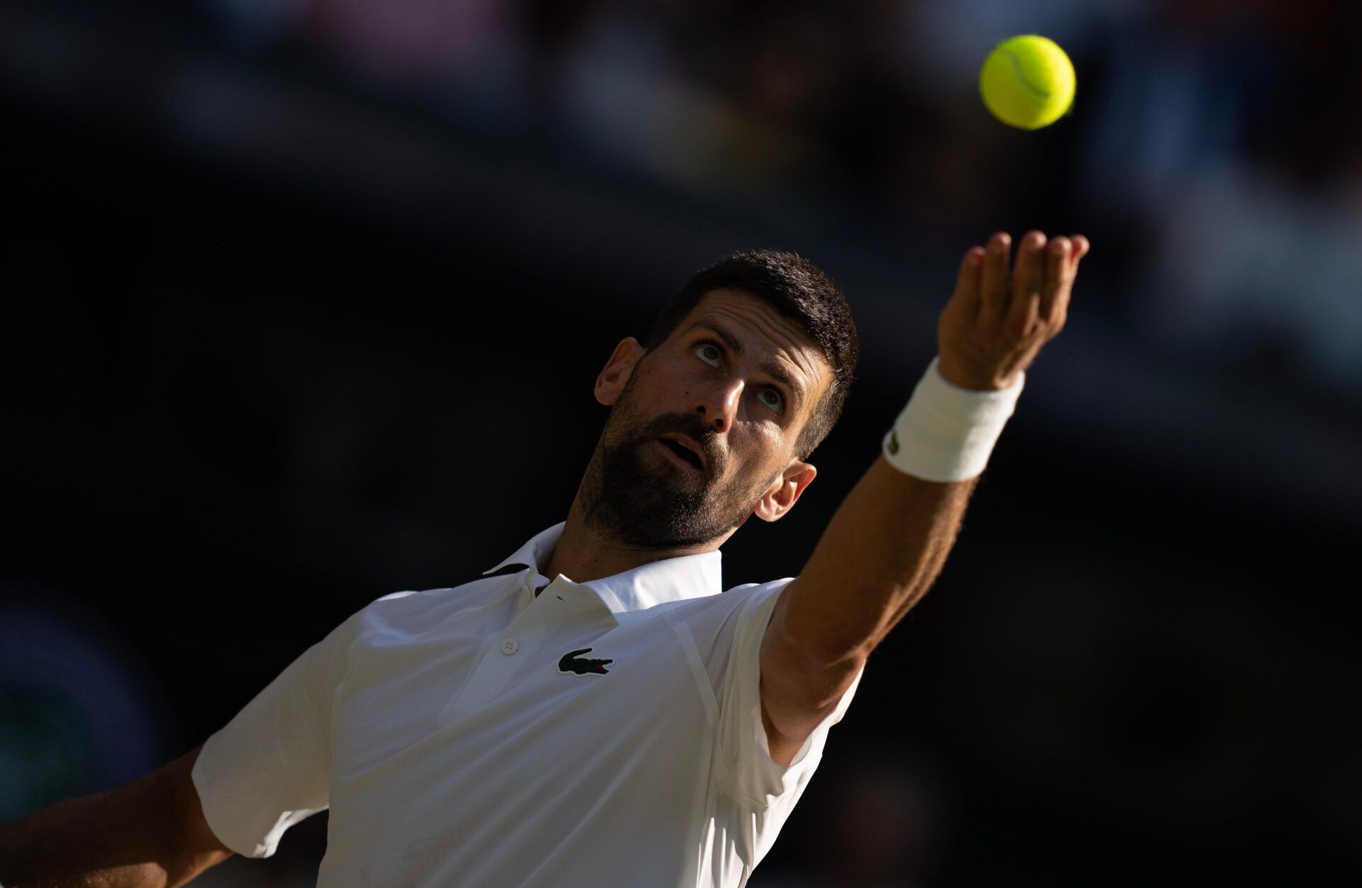 Novak Djokovic of Serbia tosses the ball to serve during his match to Jannik Sinner of Italy after their match on day 12 at All England Lawn Tennis and Croquet Club.