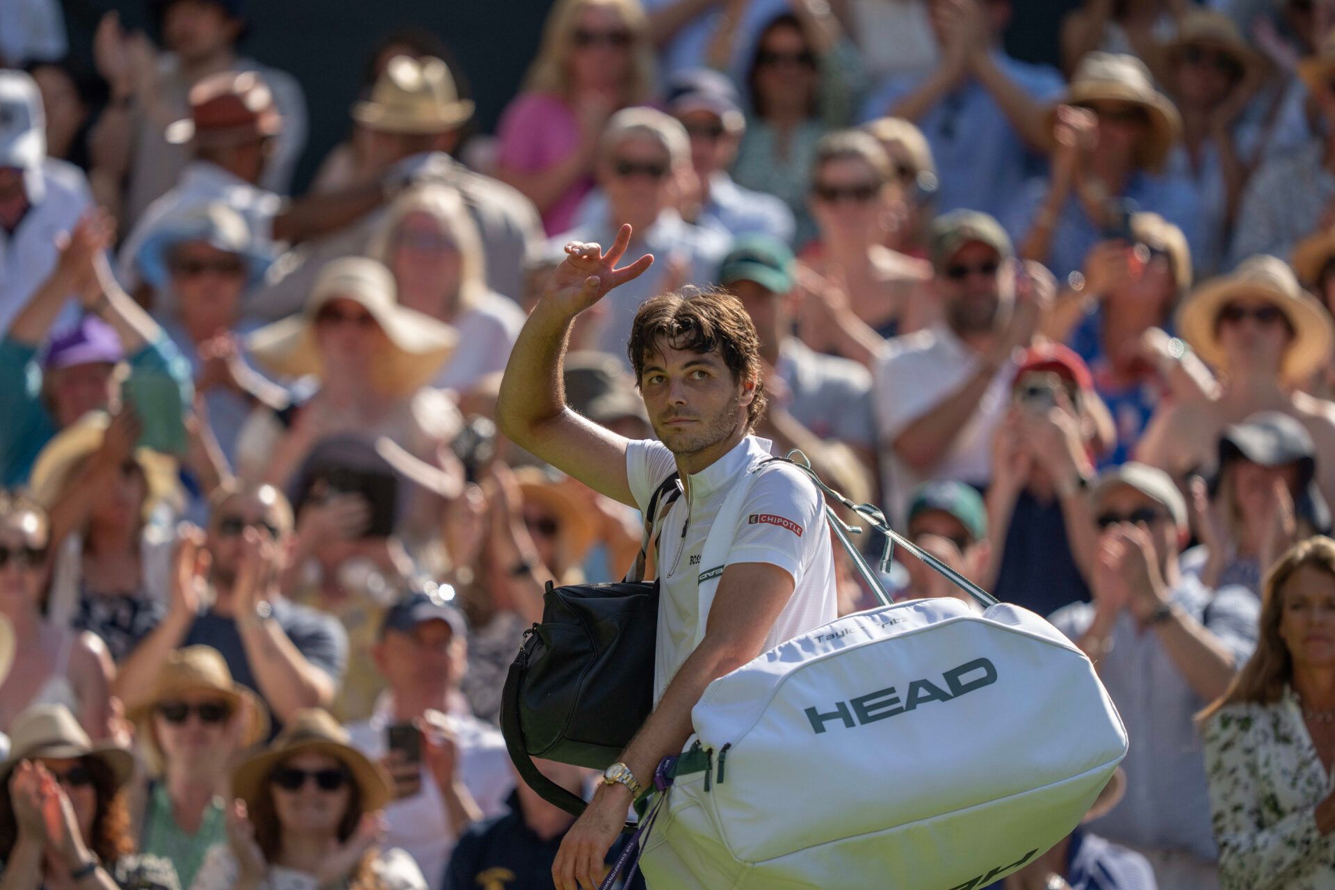 Taylor Fritz of the United States waves as he leaves the court after losing his match against Carlos Alcaraz of Spain after their match on day 12 at All England Lawn Tennis and Croquet Club.