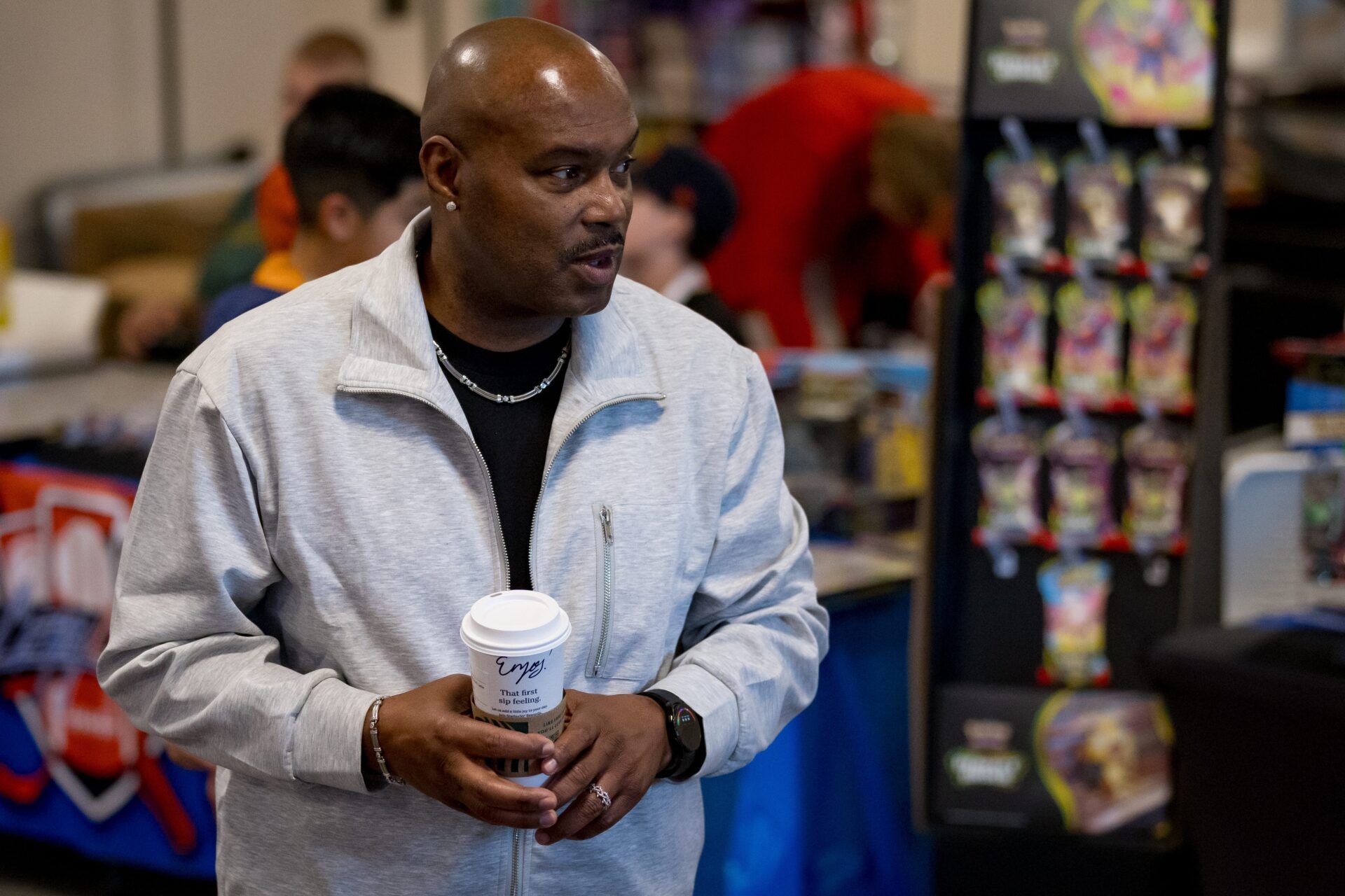 Tim Hardaway holds a cup of coffee while waiting for fans during the Sun City Card Show at the Starlight Event Center in El Paso, Texas, on Saturday, March 28, 2026. Hardaway is a former UTEP Miners basketball standout and NBA player.