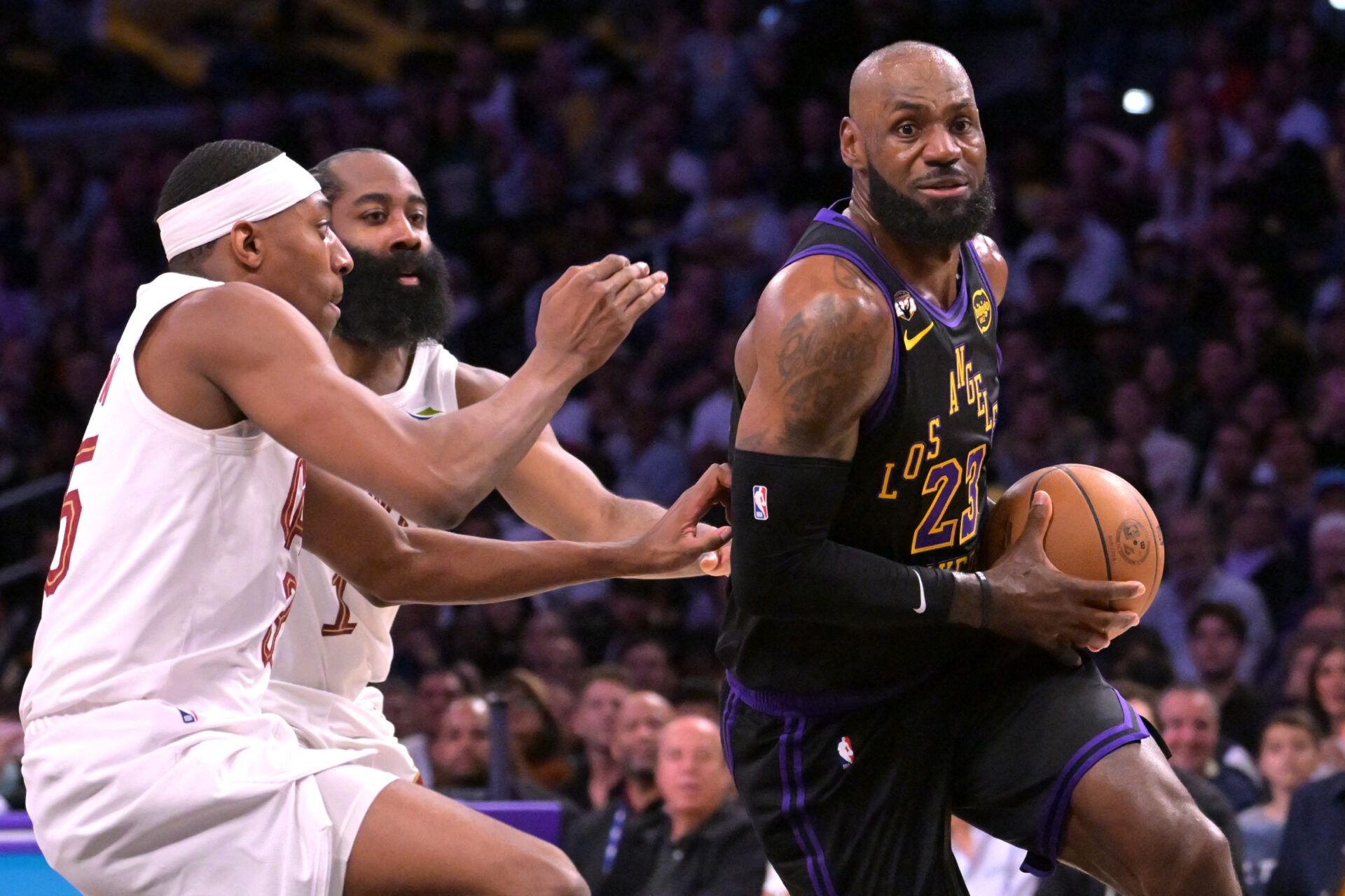 Los Angeles Lakers forward LeBron James (23) is defended by Cleveland Cavaliers guard James Harden (1) and forward Nae'qwan Tomlin (35) in the first half at Crypto.com Arena.