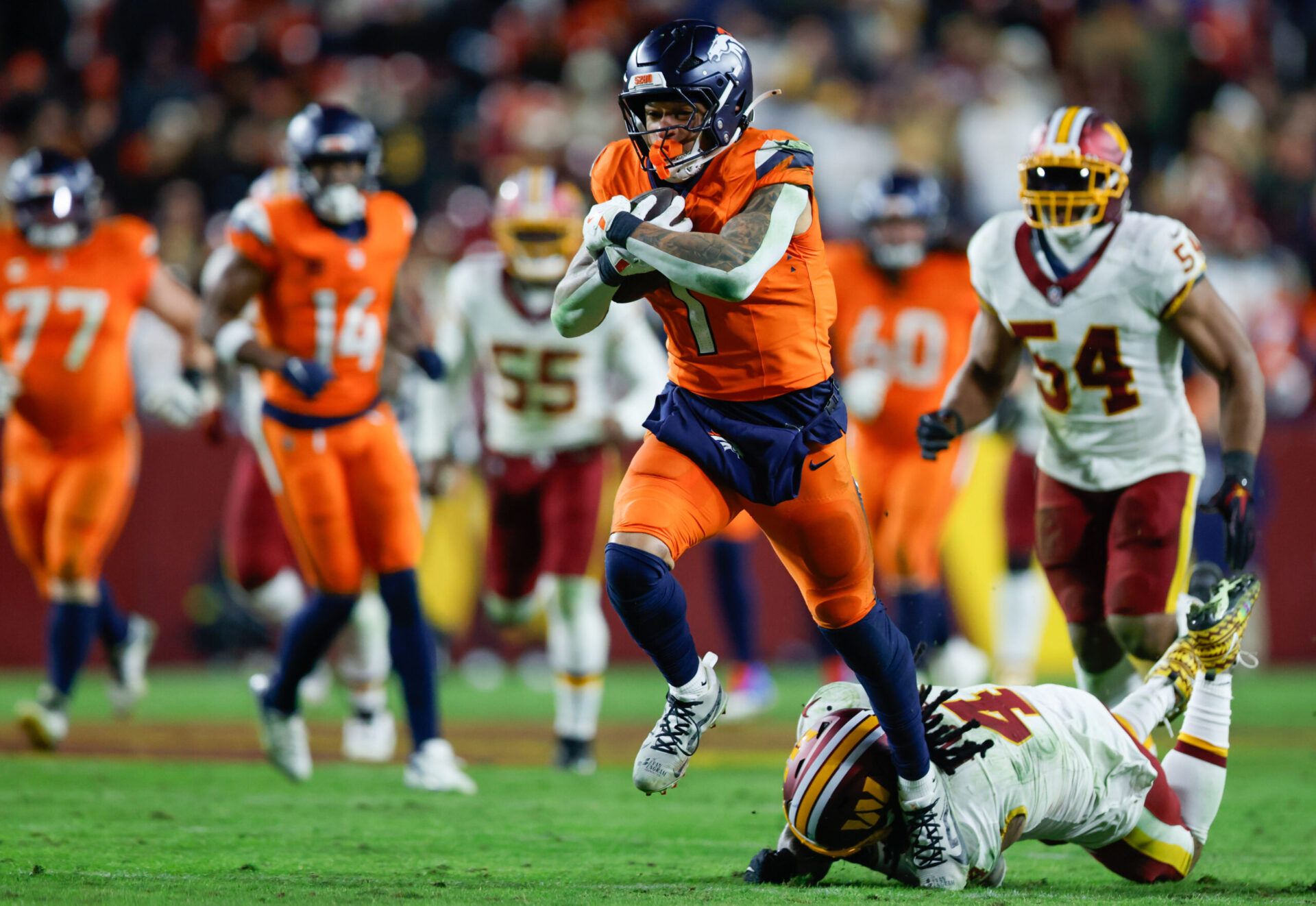 Denver Broncos tight end Evan Engram (1) avoids a tackle by Washington Commanders linebacker Frankie Luvu (4) in overtime of the game at Northwest Stadium.