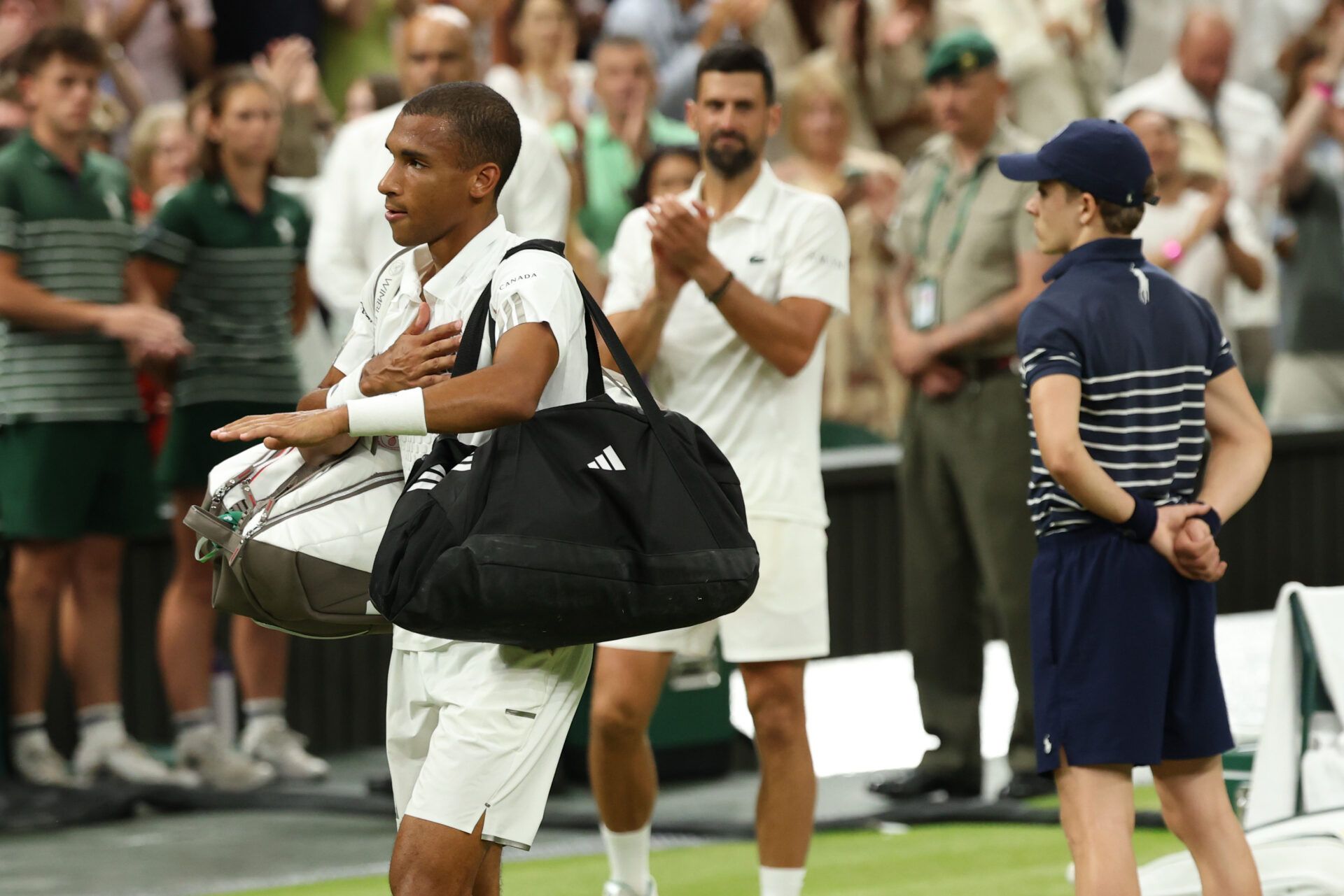 Felix Auger-Aliassime (CAN) gestures to the crowd while leaving the court after his match against Novak Djokovic (SRB) (background) on day nine of The Championships Wimbledon 2026 at All England Lawn Tennis and Croquet Club.