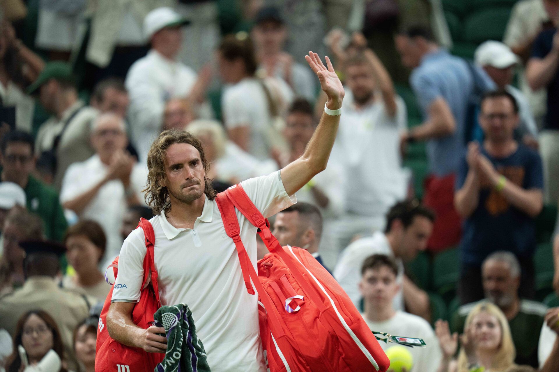 Stefanos Tsitsipas of Greece waves as he leaves the court after losing his match against Novak Djokovic of Serbia on day three at All England Lawn Tennis and Croquet Club.