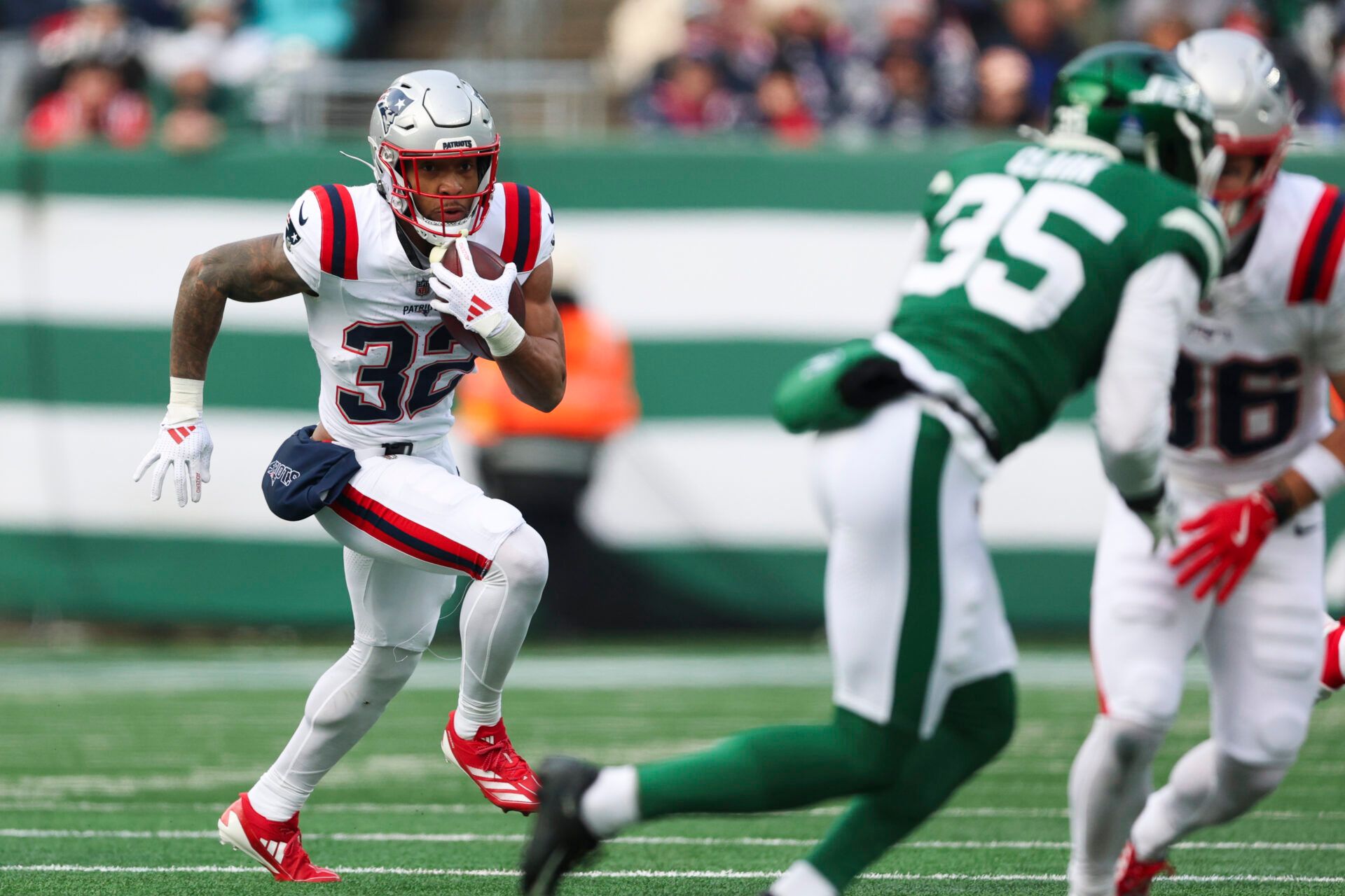 New England Patriots running back Treveyon Henderson (32) runs the ball against the New York Jets during the first quarter of the game at MetLife Stadium.