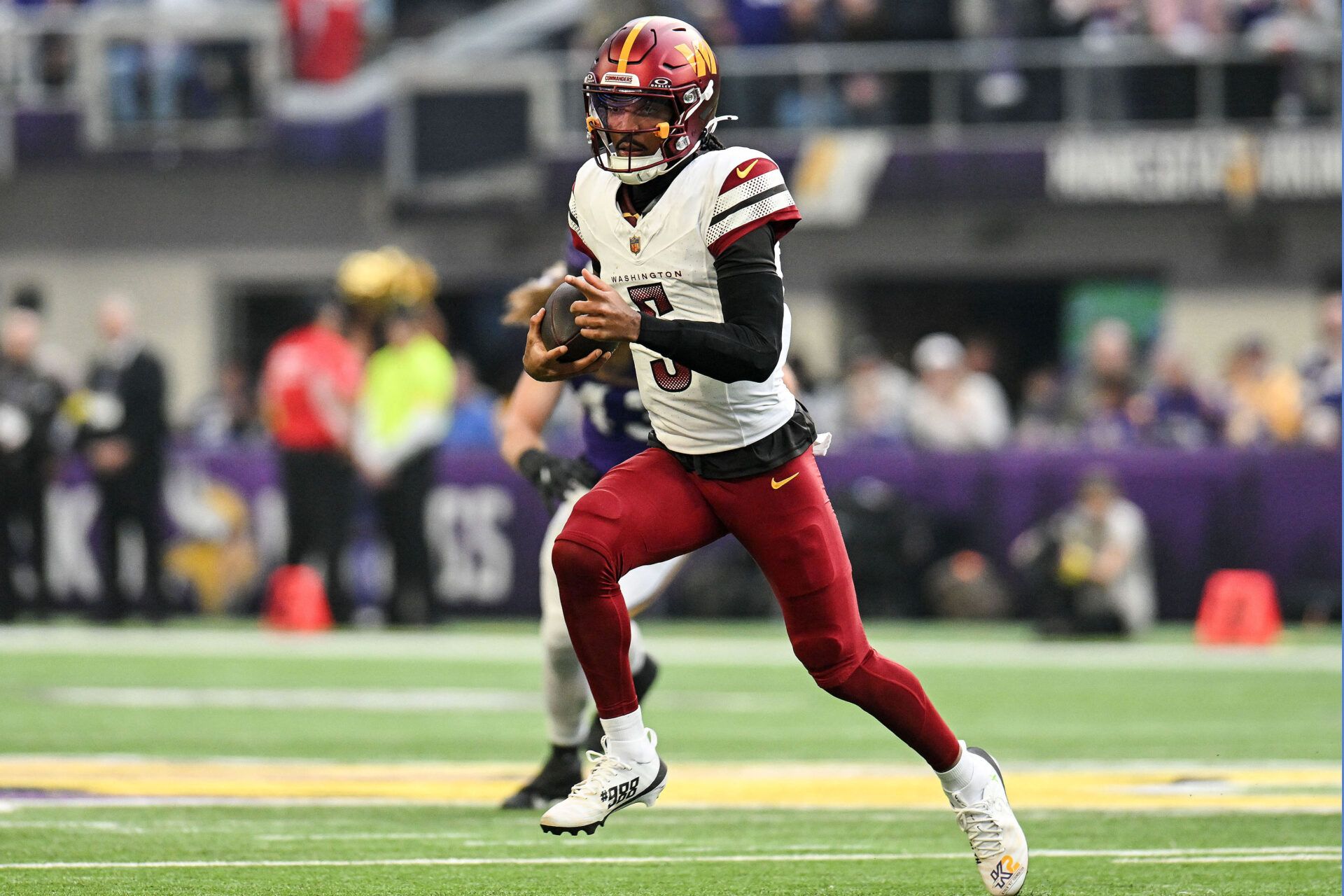 Washington Commanders quarterback Jayden Daniels (5) rushes the ball against the Minnesota Vikings during the first half at U.S. Bank Stadium.
