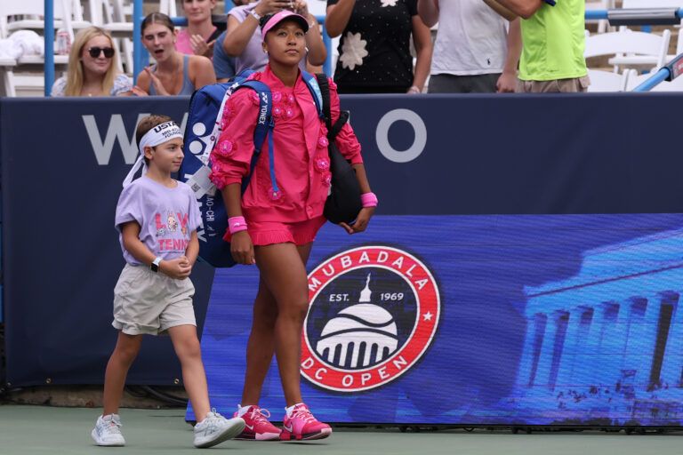 Naomi Osaka (JPN) walks onto the court with her player escort prior to her match against Ashlyn Krueger (USA) (not pictured) on day three of the 2026 Mubadala DC Open at Rock Creek Park Tennis Center.