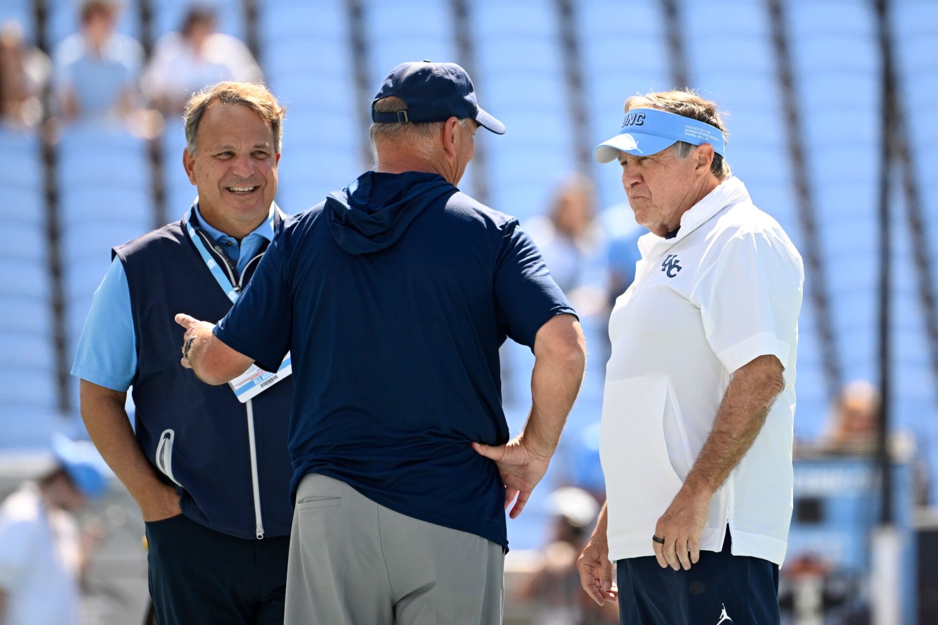 Richmond Spiders head coach Russ Huesman talks to North Carolina Tar Heels general manger Michael Lombardi and head coach Bill Belichick before the game at Kenan Stadium.