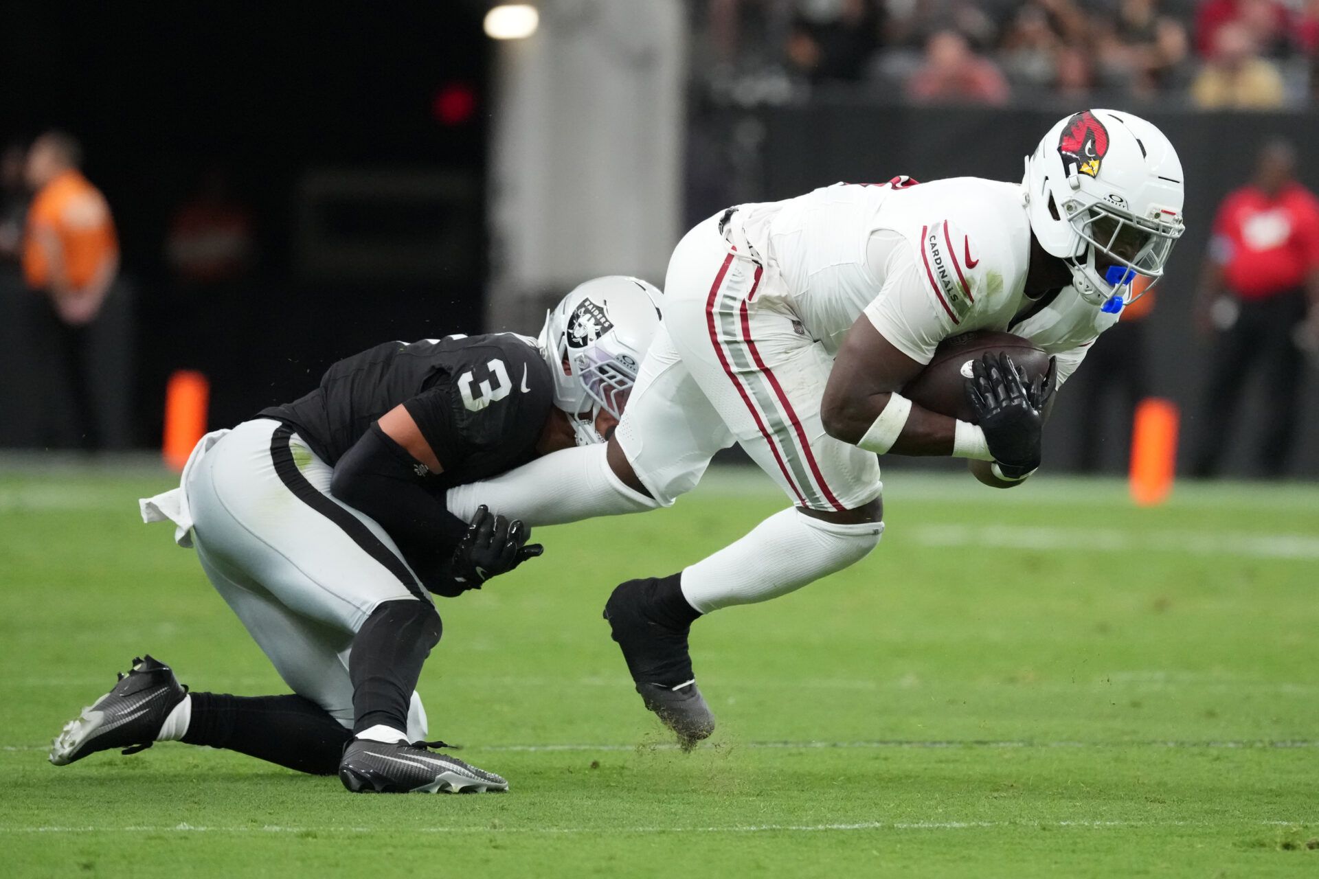 Arizona Cardinals running back Jeremiyah Love (4) carries the ball against Las Vegas Raiders cornerback Taron Johnson (3) in the first half at Allegiant Stadium.