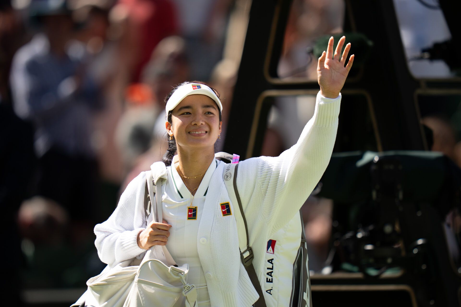 Alexandra Eala of the Philippinesr waves as she leaves the court after winning her match against Iga Swiatek of Poland on day six at All England Lawn Tennis and Croquet Club.