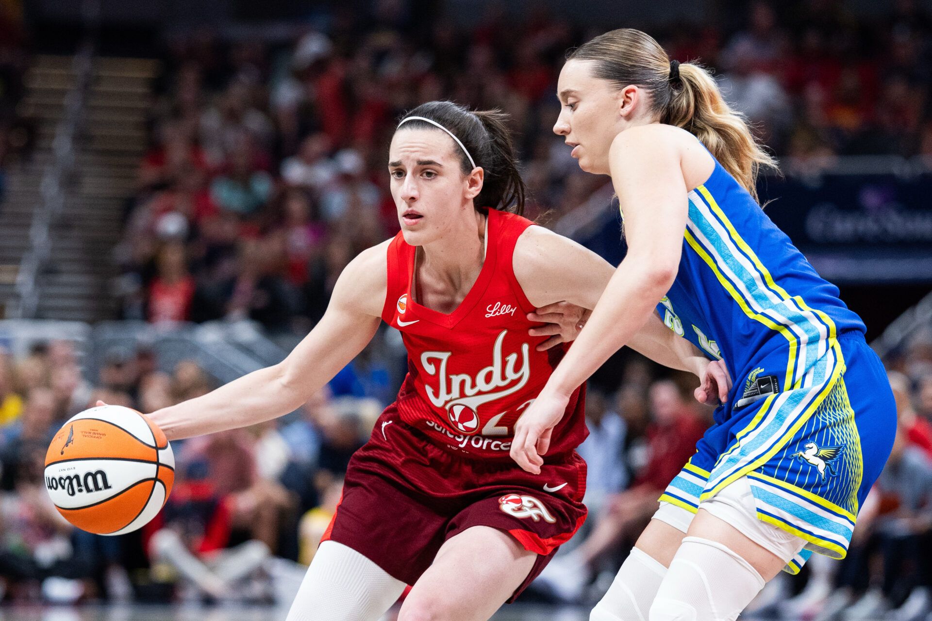 Indiana Fever guard Caitlin Clark (22) dribbles the ball while Dallas Wings guard Paige Bueckers (5) defends in the first half at Gainbridge Fieldhouse.