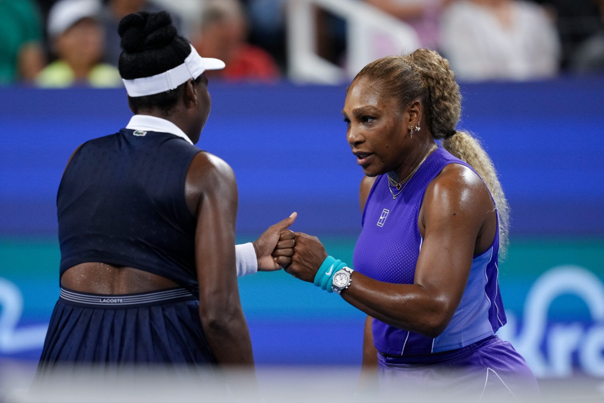 Serena Williams and Venus Williams of the United States fist bump after a point against Marta Kostyuk of Ukraine and Peyton Stearns of the United States in their doubles match during the Cincinnati Open at Lindner Family Tennis Center.