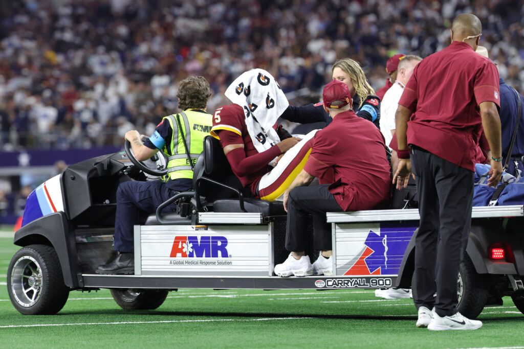 Washington Commanders quarterback Jayden Daniels (5) is carted off the field with an apparent injury to his left arm during